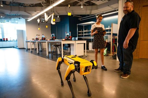 一名学生和一名教授在斯文森大厅的波士顿动力公司操作一只机器狗.