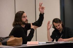 Two students raise their hands in a class